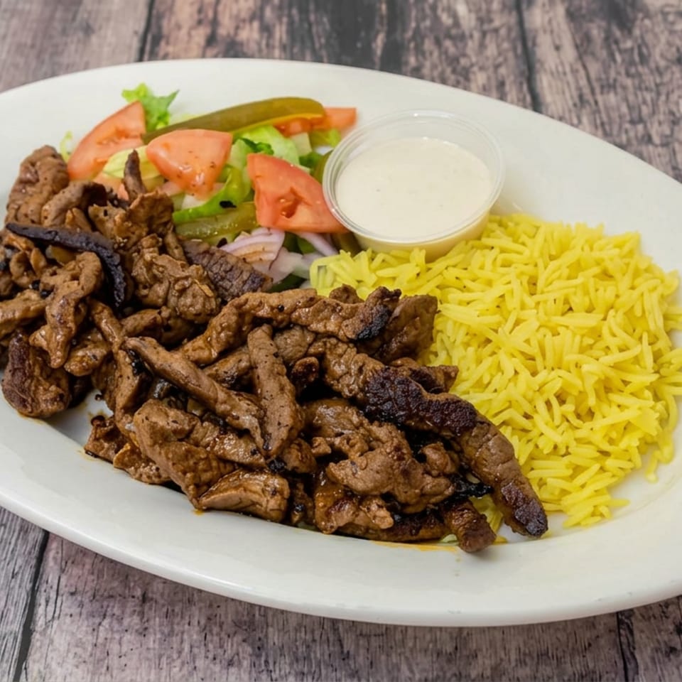 Plate of grilled beef strips with yellow rice, fresh salad, and creamy dipping sauce on a wooden table.